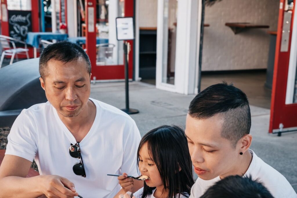 Una familia comiendo helado en la vereda de una heladería: la salida familiar que define el Día de las Infancias