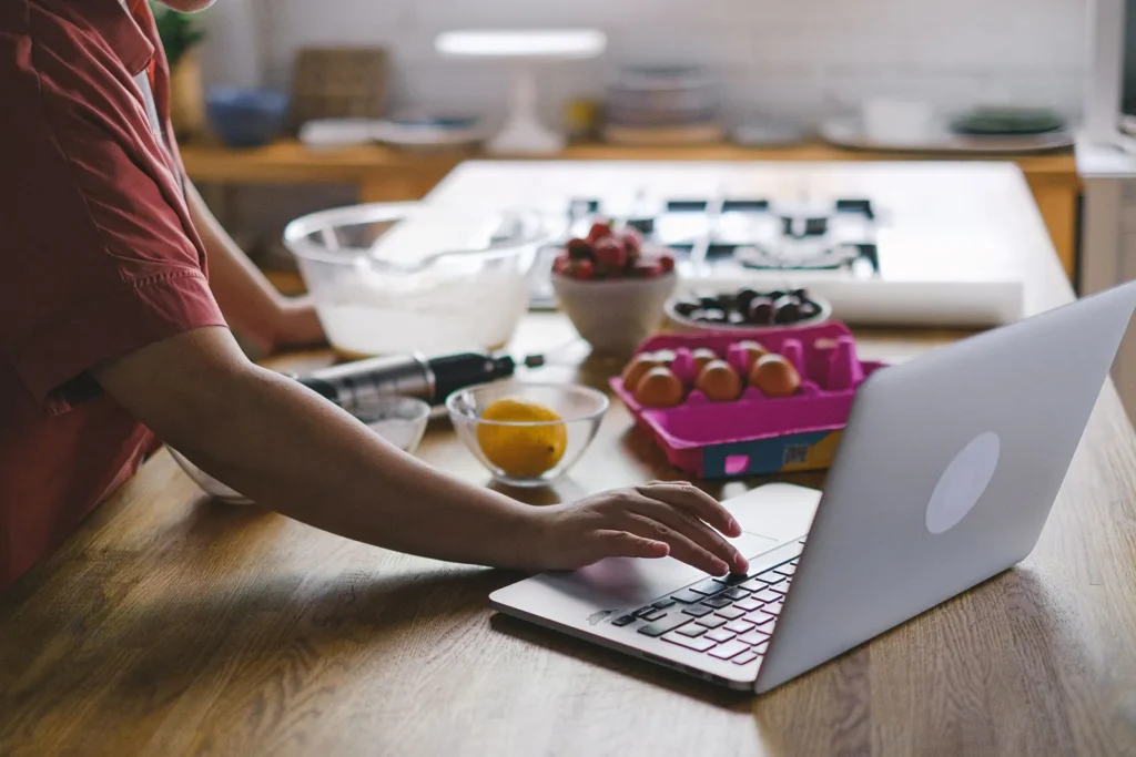 Una notebook abierta sobre la mesada, entre ingredientes, para seguir una clase online mientras se practica