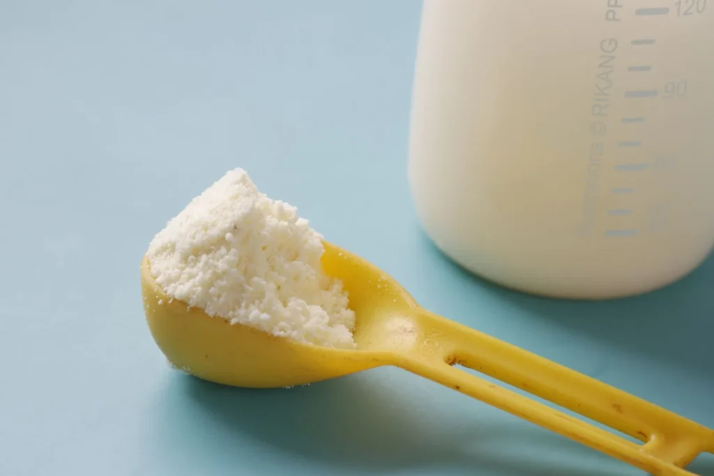 Una medida de leche en polvo junto a una botella de leche: la fuente habitual de sólidos lácteos no grasos