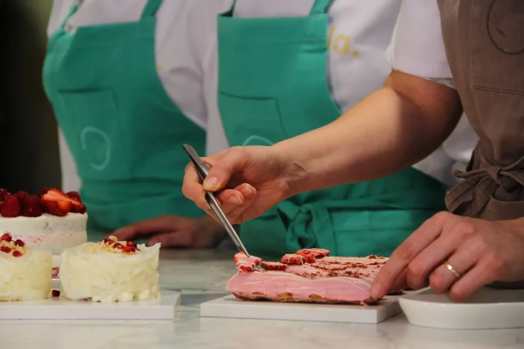 Manos de profesionales con delantal trabajando en la mesa de producción de postres helados